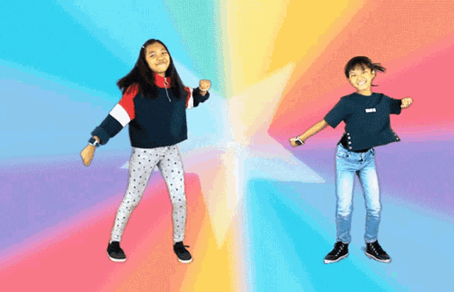 two girls are dancing in front of a colorful background and one has the word love on her shirt