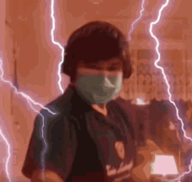 a person wearing a mask and headphones is standing in front of a lightning storm .