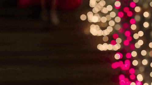 a blurry picture of a christmas tree with pink and white lights on it .