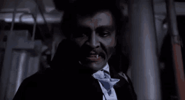 a man in a suit and tie with blood on his face is standing in a dark room looking at the camera .