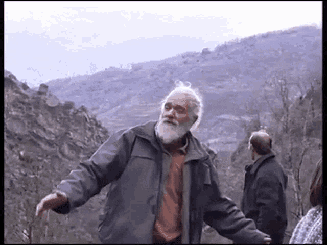 a man with a beard is standing in front of a mountain