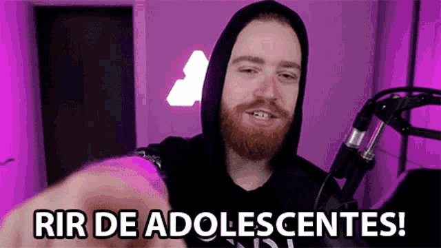 a man with a beard is pointing at the camera with the words rir de adolescentes written on the screen behind him .