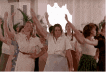 a group of women are dancing in a room with their hands in the air