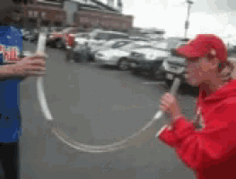 a man in a red hat is holding a microphone while another man in a blue shirt holds a stick