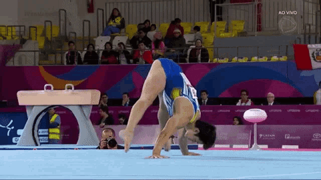 a female gymnast is doing a handstand in front of a podium that says " ao vivo "
