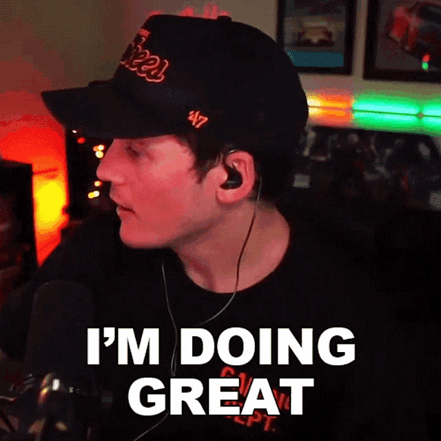 a man wearing a hat and earbuds says " i 'm doing great "