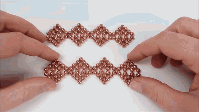 a person is holding a string of copper beads