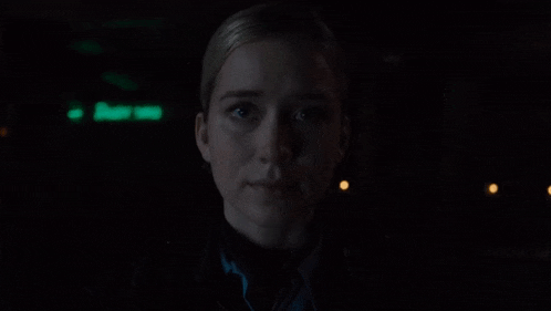 a close up of a woman 's face in the dark with a green light behind her .