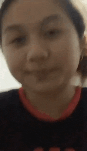 a close up of a woman 's face with a red collar and a black shirt .
