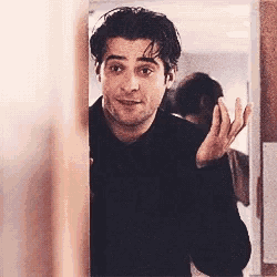 a man in a black shirt is standing behind a door