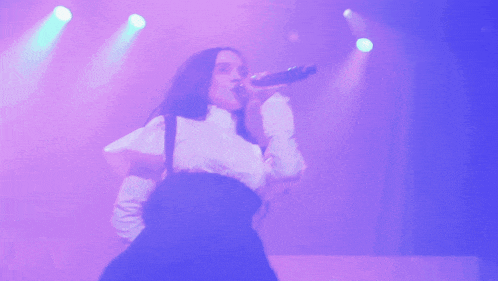 a woman singing into a microphone on a stage