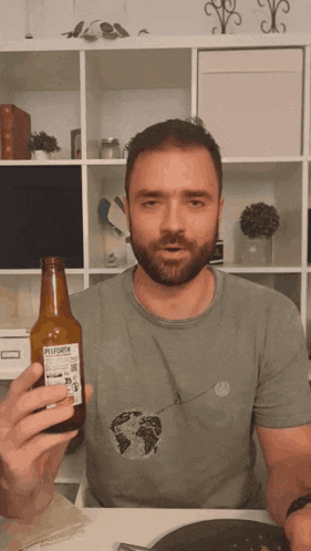 a man in a green shirt is holding a bottle of pilsner beer