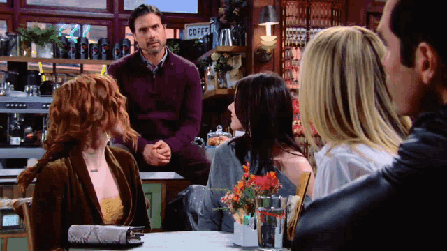 a group of people are sitting at a table in front of a coffee sign