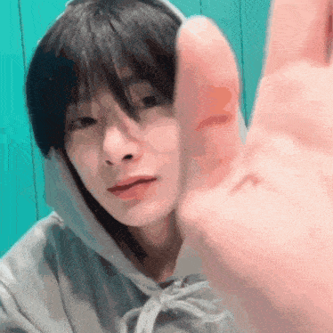 a close up of a person 's face with a hand reaching out towards it .