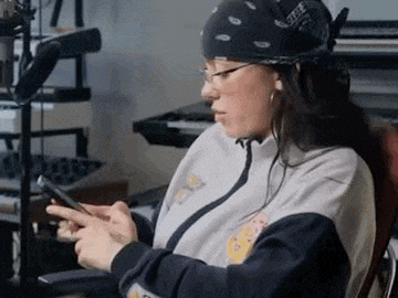 a woman is sitting in a chair looking at her cell phone .
