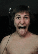 a shirtless man wearing headphones sticks out his tongue
