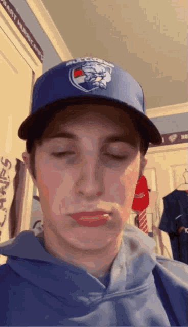 a young man wearing a blue hat with a bulldogs logo