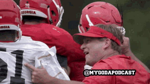 a group of georgia football players are huddled together with a man in a red shirt pointing