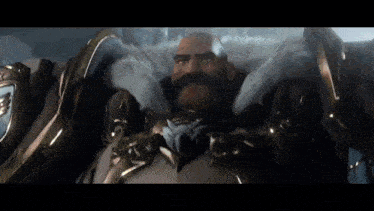a bald man with a beard is wearing armor and a crown .