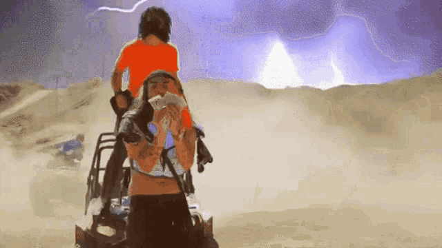 a man in an orange shirt is riding on the back of a woman in a desert