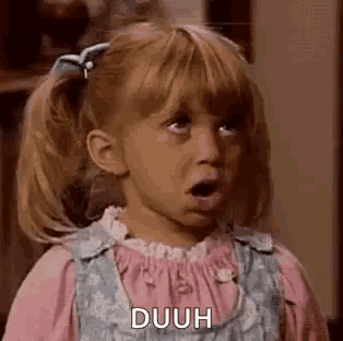 a little girl is making a funny face with her mouth open and a surprised look on her face .