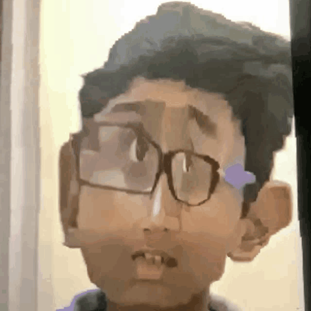 a close up of a boy wearing glasses and making a funny face .