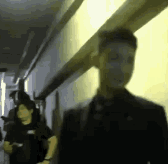 a blurry picture of a man standing in a hallway with a woman standing behind him .