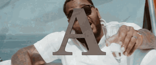 a man holding a glass with the letter a in the background