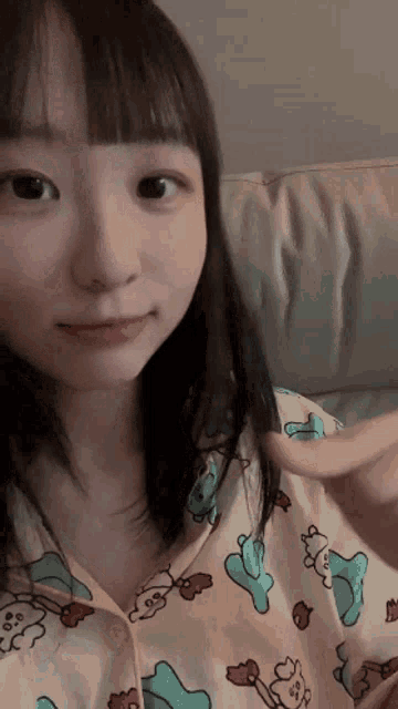 a girl is sitting on a couch wearing pajamas with cartoon characters on them .