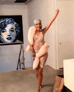 a woman is dancing in a room in front of a painting of a woman .