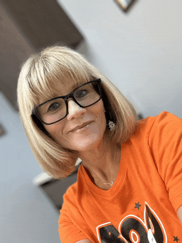 a woman wearing glasses and an orange shirt says boo