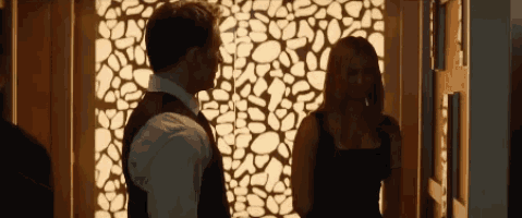 a man and woman are standing in front of a wall with a pattern