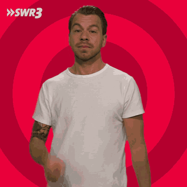 a man in a white t-shirt is waving his hand in front of a red circle with swr3 written on it