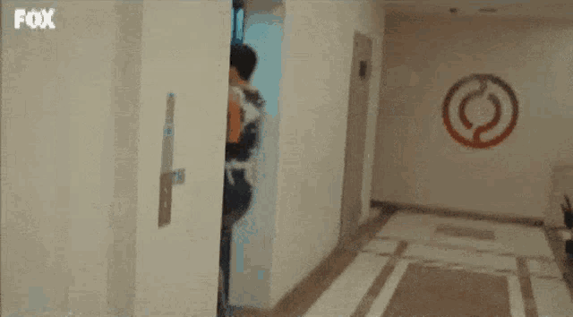 a man is getting out of an elevator with a fox logo on the wall .