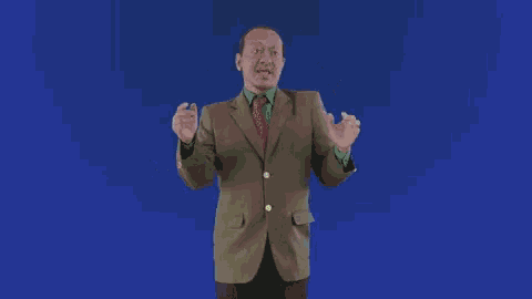 a man in a suit and tie is dancing with his hands in the air