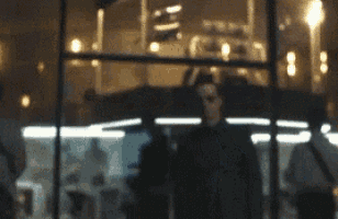 a man is standing in front of a window at night .