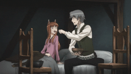 a man and a girl are sitting on a bed and the man is feeding the girl