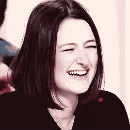 a close up of a woman laughing with her eyes closed and her mouth open .