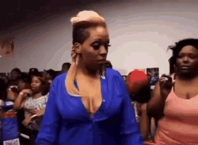 a woman in a blue shirt is standing in a crowd of people at a party .