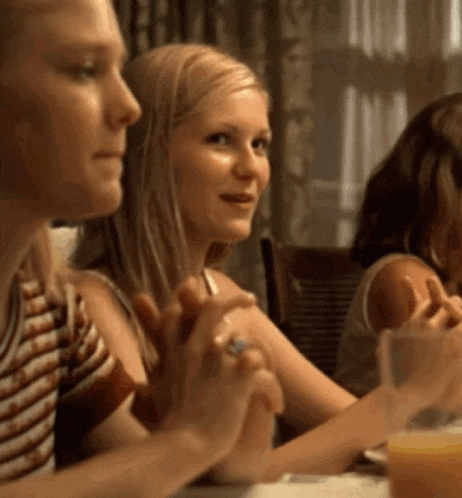 a woman with a ring on her finger sits at a table with other women
