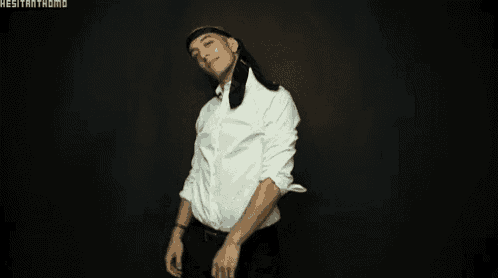 a man in a white shirt and black tie is dancing in the dark .