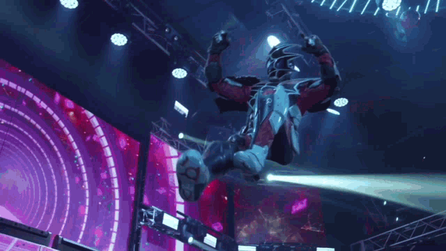 a man in a superhero costume is flying through the air on a stage