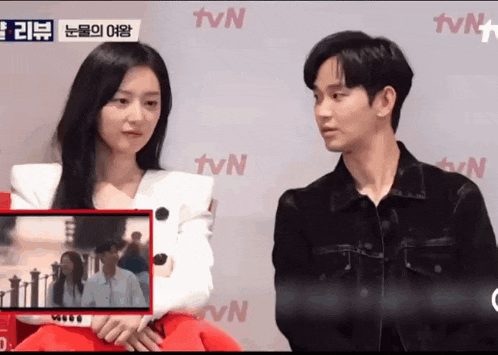 a man and a woman are standing next to each other in front of a tvn banner .