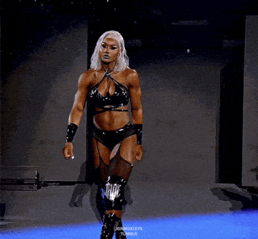 a female wrestler in a black outfit is walking on a stage
