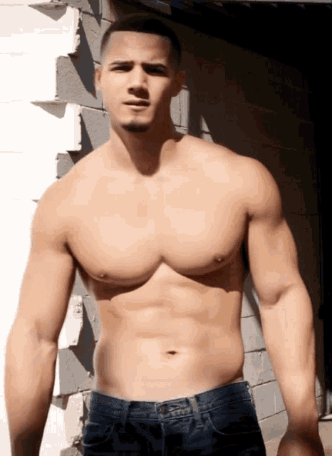a shirtless man is standing in front of a white wall
