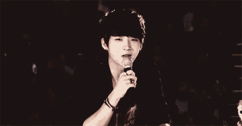 a young man is holding a microphone in his hand and making a funny face .