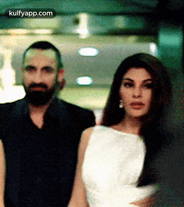 a man and a woman are standing next to each other . the woman is wearing a white dress .