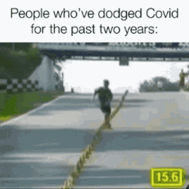 a man is running down a road with a sign that says 15.6 on it .