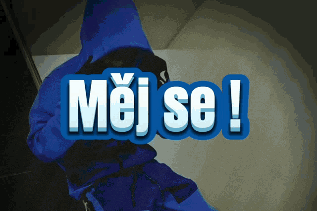 a person in a blue hoodie stands in front of a sign that says moj se !