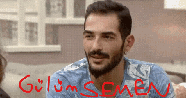 a man with a beard is smiling with the words gülüm semen written in red